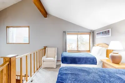 a bedroom with two beds and a chair and a window at Buffalo Ridge Retreat in Silverthorne
