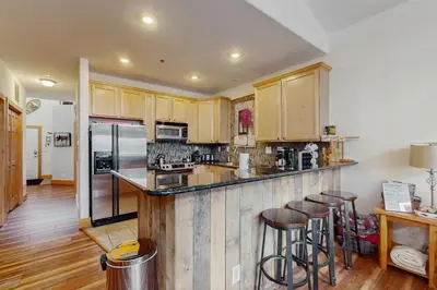 a kitchen with wooden cabinets and a bar with stools at La Riva Del Lago 209 in Dillon