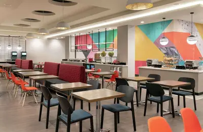 a restaurant with tables and chairs and a counter at Tru By Hilton Denver Downtown Convention Center in Denver