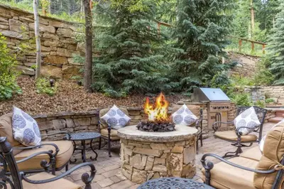 a fire pit in a yard with chairs and a table at Premier 4 Bedroom Ski In, Ski Out Vacation Rental At The Timbers With The Best Access To Skiing In Keystone in Keystone