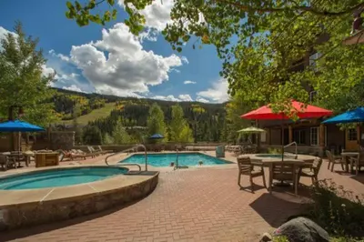 a swimming pool with a table and chairs and a patio at Spacious 4 Bedroom Townhome In River Run Village Within Walking Distance To Gondola And Restaurants in Keystone