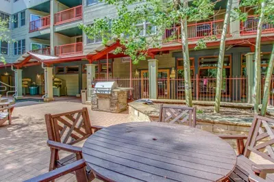 a wooden table and chairs in front of a building at Luxury 1 Bedroom Mountain Condo In River Run Village With Expansive Mountain Views And Walking Distance To Ski Slopes in Keystone