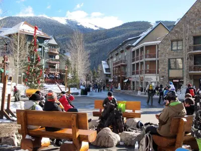 a group of people sitting on benches in a town with a christmas tree at Luxury 1 Bedroom Mountain Condo In River Run Village With Expansive Mountain Views And Walking Distance To Ski Slopes in Keystone