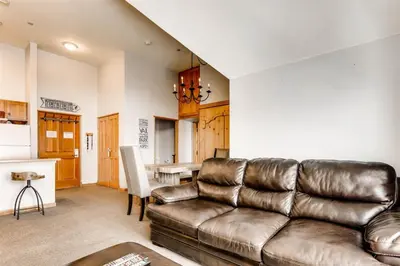 a living room with a leather couch and a kitchen at 1 Bedroom Plus Murphy Mountain Condo In River Run Village With Mountain Views And Walking Distance To Ski Slopes in Keystone