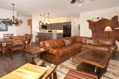 a living room with a brown leather couch and a table at Ski In 2 Bedroom At Chateaux Dumont Keystone in Keystone