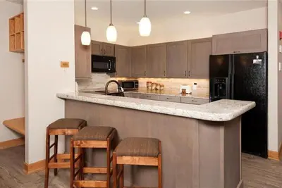 a kitchen with a counter with stools and a sink at Ski In 2 Bedroom At Chateaux Dumont Keystone in Keystone