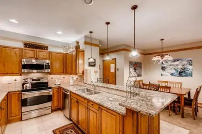 a large kitchen with wooden cabinets and a dining room at Ski In 3 Bedroom At Chateaux Dumont Keystone in Keystone
