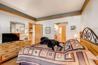 a teddy bear laying on a bed in a bedroom at Ski In 3 Bedroom At Chateaux Dumont Keystone in Keystone