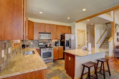 a large kitchen with wooden cabinets and a counter top at Private 2 Bedroom Townhome Located In East Keystone With Access To A Firepit, Hot Tub, And Billiards in Keystone