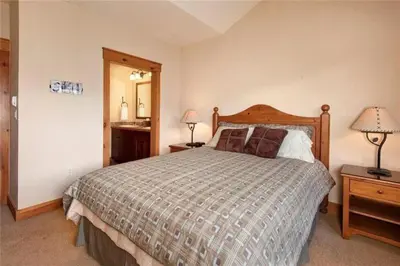 a bedroom with a bed and two lamps and a mirror at Private 3 Bedroom Townhome Located In East Keystone With Access To A Firepit, Hot Tub, And Billiards in Keystone