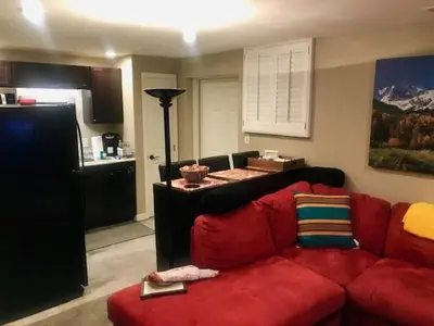 a living room with a red couch and a kitchen at Denver Blue Bear Den 3BR 2BA & Spa in Denver