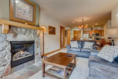 a living room with a stone fireplace and couches at Premier Red Hawk Lodge 2 Br-Walk To Slopes-Kids Ski Free Condo in Keystone
