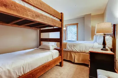 a bedroom with two bunk beds and a lamp at Premier Red Hawk Lodge 2 Br-Walk To Slopes-Kids Ski Free Condo in Keystone