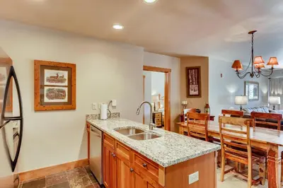 a kitchen with a sink and a dining room at Premier Red Hawk Lodge 2 Br-Walk To Slopes-Kids Ski Free Condo in Keystone