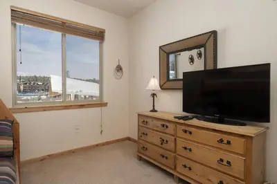 a living room with a flat screen tv on a dresser at Trailhead Lodge 734 Condo in Winter Park