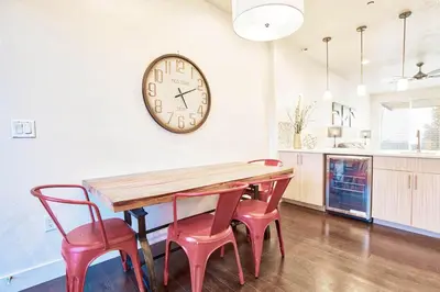 a dining room table with four chairs and a clock on the wall at Beautiful 3 Bedroom Townhouse in Old Town North, Brewery District in Fort Collins