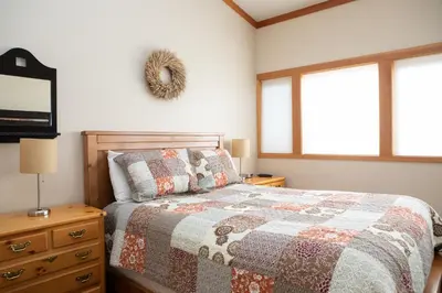 a bedroom with a bed and a dresser and two windows at 1320 Tennis Townhome Townhouse in Keystone
