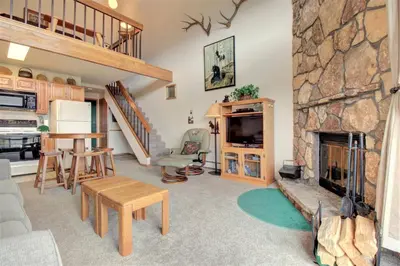 a living room with a stone fireplace and a table and chairs at Dd402E Buffalo Village Studio Condo in Silverthorne
