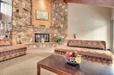 a living room with two beds and a stone wall at Dd402E Buffalo Village Studio Condo in Silverthorne
