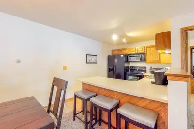 a kitchen with a counter with stools and a refrigerator at Buffalo Village in Silverthorne