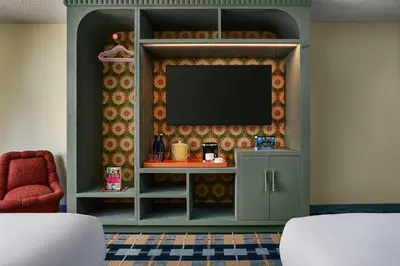 a living room with a tv on a wall at the Curtis Denver - A DoubleTree by Hilton Hotel in Denver