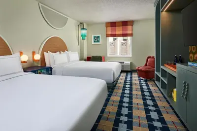 a hotel room with two beds and a chair at the Curtis Denver - A DoubleTree by Hilton Hotel in Denver