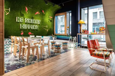 a dining room with a green wall with a table and chairs at the Curtis Denver - A DoubleTree by Hilton Hotel in Denver