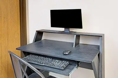 a desk with a computer monitor and a keyboard and mouse at Super 8 by Wyndham Fort Collins in Fort Collins