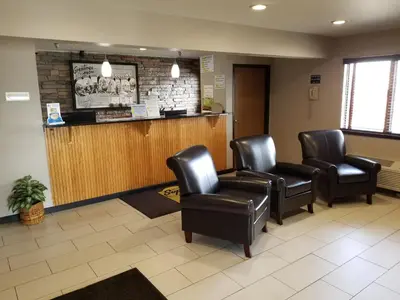 a waiting room with leather chairs and a bar at Super 8 by Wyndham Fort Collins in Fort Collins