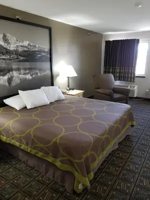 a hotel room with a bed and a chair at Super 8 by Wyndham Fort Collins in Fort Collins