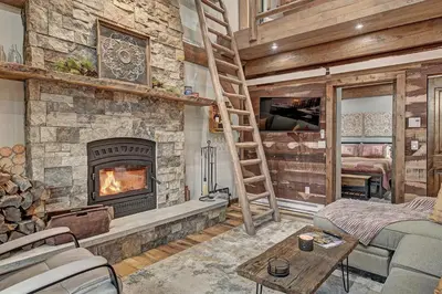 a living room with a fireplace and a ladder at SkyRun Cabin cabin in Golden