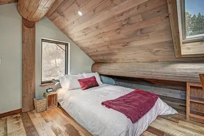 a bed in a room with a wooden wall at SkyRun Cabin cabin in Golden