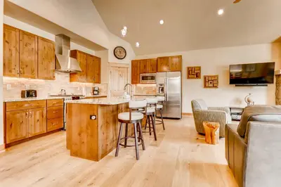 a kitchen with wooden cabinets and a bar with stools at Three-Bedroom Townhouse in Keystone