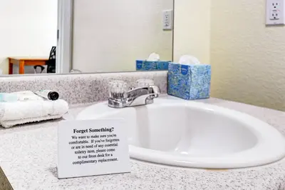a bathroom sink with a sign next to it at Suburban Studios Westminster Denver North in Westminster