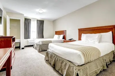 a hotel room with two beds and a television at Suburban Studios Westminster Denver North in Westminster