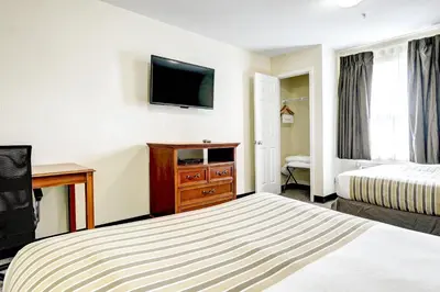 a hotel room with a bed and a flat screen tv at Suburban Studios Westminster Denver North in Westminster