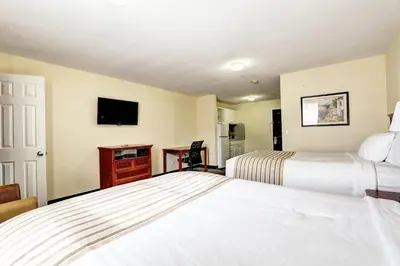a hotel room with two beds and a television at Suburban Studios Westminster Denver North in Westminster