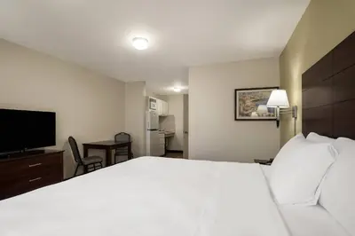 a hotel room with a white bed and a television at Suburban Studios Denver Central-Arvada in Arvada