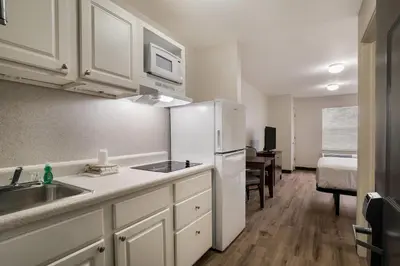 a kitchen with a white refrigerator and a bedroom at Suburban Studios Denver Central-Arvada in Arvada