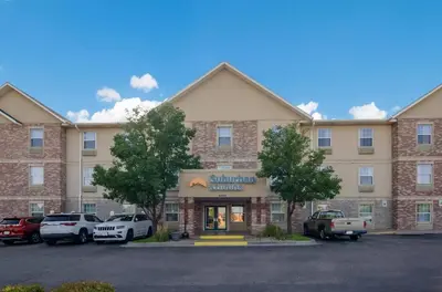 a large building with cars parked in a parking lot at Suburban Studios Denver Central-Arvada in Arvada
