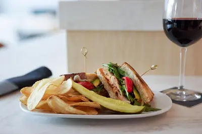 a sandwich and chips on a plate with a glass of wine at AC Hotel Frisco Colorado in Frisco