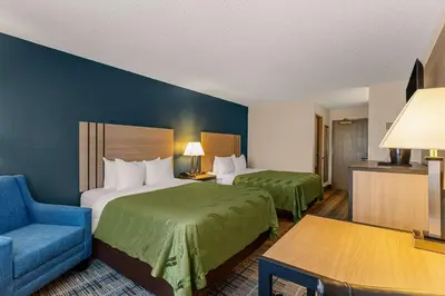 a hotel room with two beds and a blue chair at Quality Inn Denver Northeast Brighton in Brighton