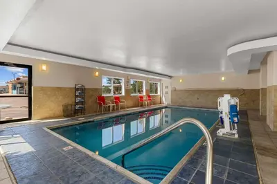 a swimming pool in a hotel with red chairs at Quality Inn Denver Northeast Brighton in Brighton