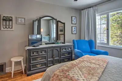 a bedroom with a dresser with a mirror and a blue chair at Outdoor Kitchen and Swim Spa 1-Acre Grand Lake Home in Grand Lake