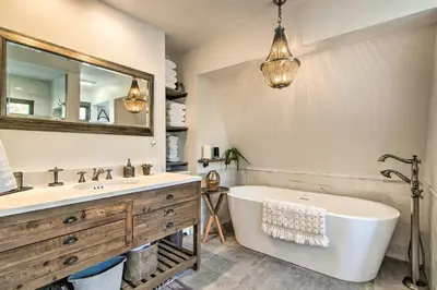a bathroom with a tub and a sink and a mirror at Outdoor Kitchen and Swim Spa 1-Acre Grand Lake Home in Grand Lake