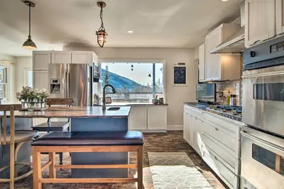 a large kitchen with white cabinets and a large window at Outdoor Kitchen and Swim Spa 1-Acre Grand Lake Home in Grand Lake