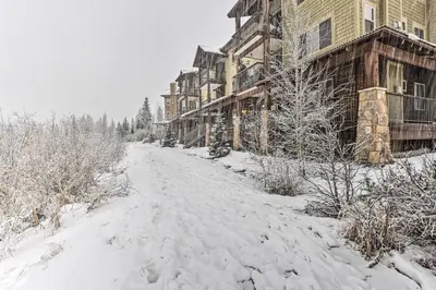 a snow covered road in front of a building at Four-Season Winter Park Condo with Pool Access! in Winter Park