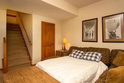 a bedroom with a bed and a couch and stairs at 45 Reunion Court - Rendezvous in Fraser