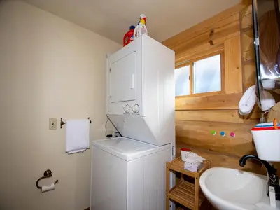 a bathroom with a white refrigerator and a sink at Miles Behind Log Cabin in Fraser
