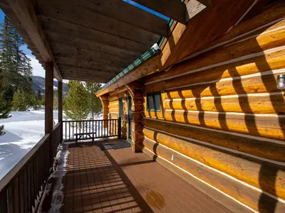 a porch of a log cabin with snow on the ground at Miles Behind Log Cabin in Fraser